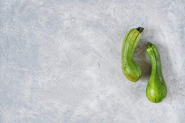 Two spoiled zucchini on a gray background. Ugly food concept, organic vegetables. Top view, flat...