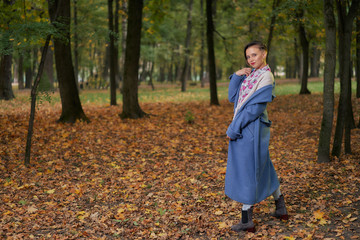 Portrait of young urban style woman standing at park. Autumn season. Copy space.