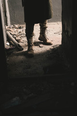 cropped view of man in boots standing in old room, post apocalyptic concept