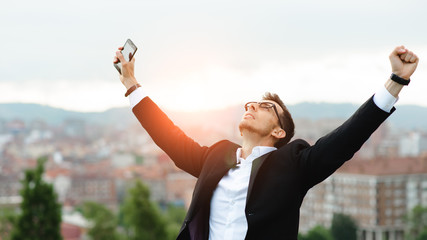 Young successful entrepreneur looking smartphone