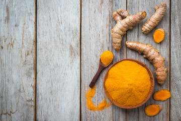 Turmeric powder and roots on wooden background, asian herb for medication, flay lay concept