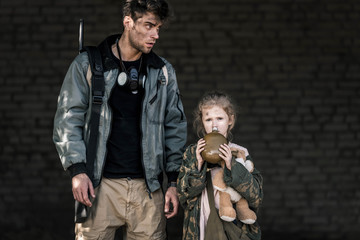 handsome man standing near kid with flask, post apocalyptic concept