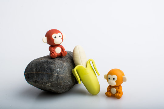 Two monkey and a banana rubber toys, cute animal shaped rubber doll isolated in white background. 