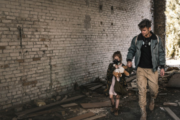 Fototapeta na wymiar man holding hands with kid while walking on street in chernobyl, post apocalyptic concept