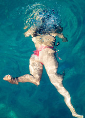 A girl swims in the blue water of the sea