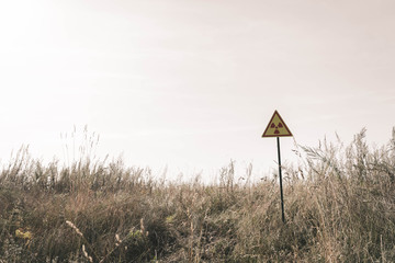 triangle with warning toxic symbol near field, post apocalyptic concept