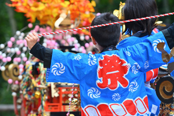 祭りの法被を着た少年とお御輿