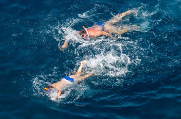 Obraz na płótnie Canvas People swim in the blue water of the sea