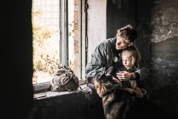 man hugging kid near german shepherd dog in abandoned building, post apocalyptic concept