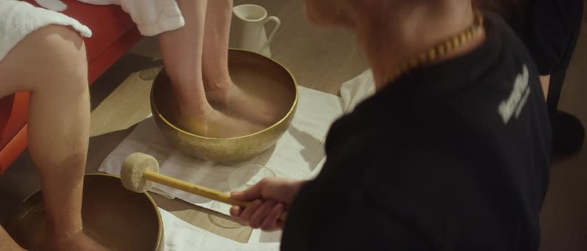 two masseuses giving a wine foot massage to a couple with the aid of a singing bowl - Zwei Masseusen geben einem Paar eine Fu&szlig;massage mithilfe einer Klangschale