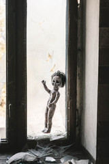 burnt baby doll near broken window and glass, post apocalyptic concept