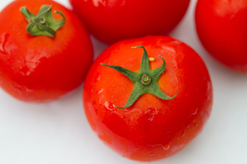 Details of a red tomato with green stipe and other blurry tomatoes in the background