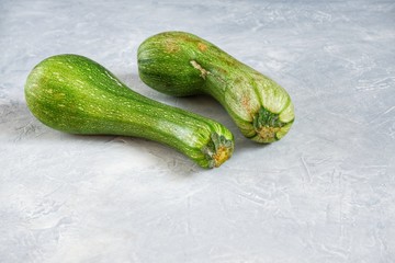 Two spoiled zucchini on a gray background. Ugly food concept, organic vegetables. Close-up, selective focus.Copy space for text.