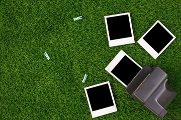 Instant photo frames and a camera on a background of lawn grass. Concept of preservation of memories. Flat lay.