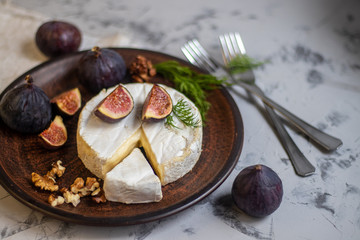 Ripe, beautiful, purple figs. Sweet and juicy. Mediterranean fruit is very healthy. On a plate is Brie cheese. On a light gray background copyspace there is an empty place. Food for vegetarians. 