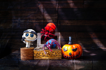 Halloween concept background, wooden doctor ghost with colorful yarn spider in treasure box and halloween pumpkin over abstract vintage wood pattern background