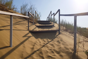 The old wooden stairs to the sand dunes. rise up. sunrise. Russia, Dagestan.