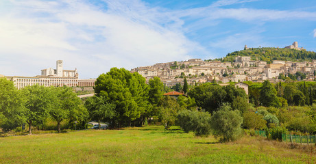 Fototapeta na wymiar Panoramic view from countryside of the historic town of Assisi in beautiful sunny day with blue sky and clouds in summer, Umbria, Italy.