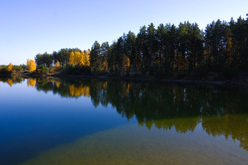 Fototapeta na wymiar Lake in a delightful autumn forest at sunny day. Autumn trees with reflection. Russia. 