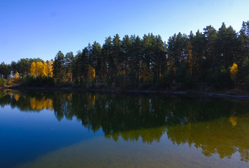 Fototapeta na wymiar Lake in a delightful autumn forest at sunny day. Autumn trees with reflection. Russia. 