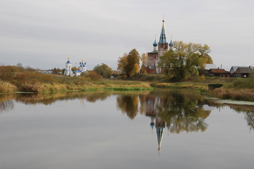 church on the river reflecting in calm water in sunny fall day