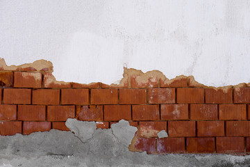 Destroyed white wall with  brick