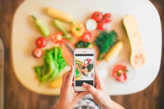 Girl makes photo on smartphone ingredients for cooking.