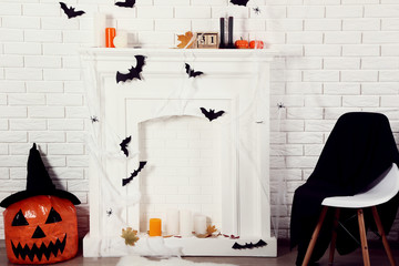 Halloween decorations on white fireplace with orange pumpkin and chair