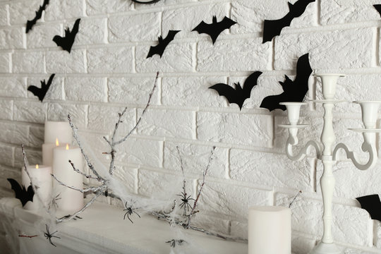 White candles with black papre bats and candlestick on brick wall background