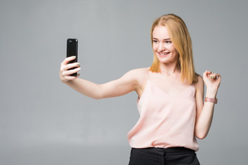Fototapeta premium Pretty teen girl taking selfies with her smart phone isolated on white background