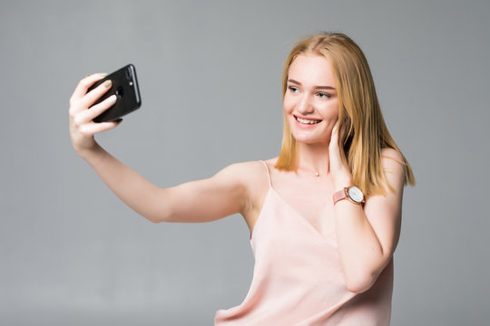 Pretty teen girl taking selfies with her smart phone isolated on white background
