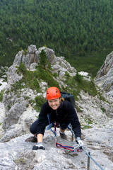 woman in her twenties climbing a steep Via Ferrata in the Dolomites of Alta Badia