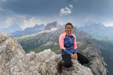 Obraz premium attractive brunette mountain climber sitting on a mountain peak and smiling