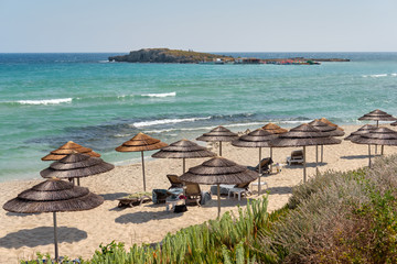 Panoramic view on a straw umbrellas and deck chairs standing at the beach of the azure mediterranean sea. Beautiful nature of Cyprus. Ayia Napa.