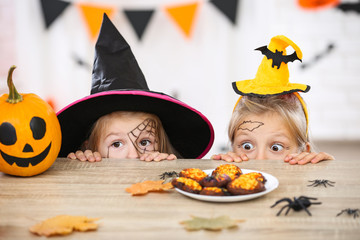 Young two girls in halloween costumes looking on the cookies