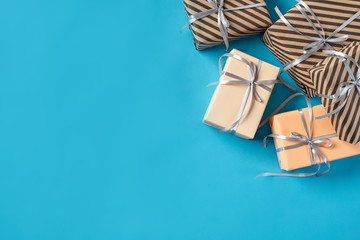 Colorful, striped and plain, brown and pink paper gift boxes tied with silver ribbons and bows on a blue background. Close-up, copy space, top view.