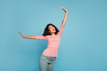 Photo of curly wavy charming overjoyed girlfriend wearing grey trousers pants screaming rock song while stretching with emotional facial expression isolated blue vivid color background