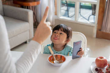 portrait of a mother get angry with stubborn kid using mobile phone