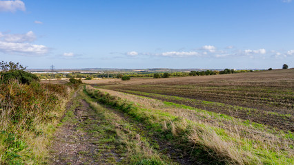 Countryside image featuring farm lands with the farm track disappearing into the distance showing fields that have just been harvested.