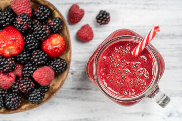 Fresh organic red smoothie in glass mug on white table, close up, top view. Refreshing summer fruit drink. Blackberry, raspberry and strawberry smoothie