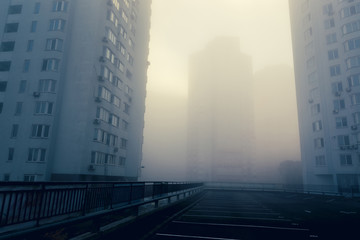 Empty parking space among residential buildings at modern urban district. Foggy morning with...