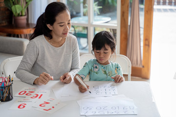 mother teaching basic math to her little daughter at home