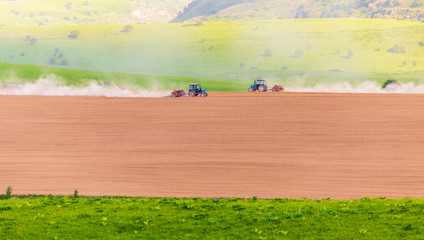 Obraz premium Dust from a tractor working in a field in spring