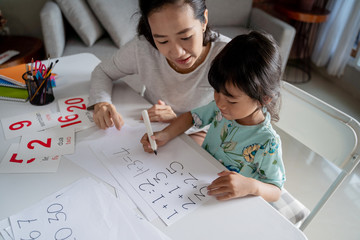 mother teaching basic math to her little daughter at home