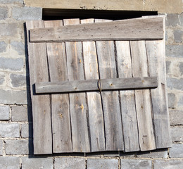 The windows of a brick house boarded up with wooden boards