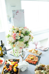 Table decorations made of artificial bouquets of flowers in a vase during catering at a wedding or events.