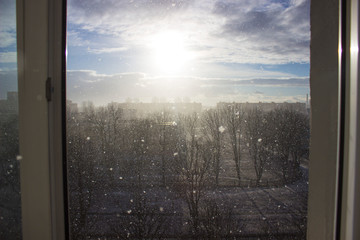 View from the window with a defocused background. Bright blue of it with the sun on a frosty day with falling snow