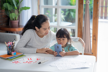 elearning of mother showing her daughter from smartphone during homeschooling activity at home