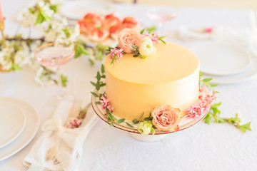 Fototapeta na wymiar Wedding cake with flowers without piece on boho style table setting.