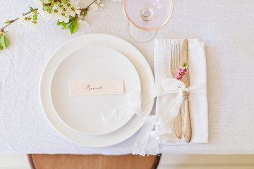 Dishes and cutlery, boho wedding table setting. Wedding card in white plate